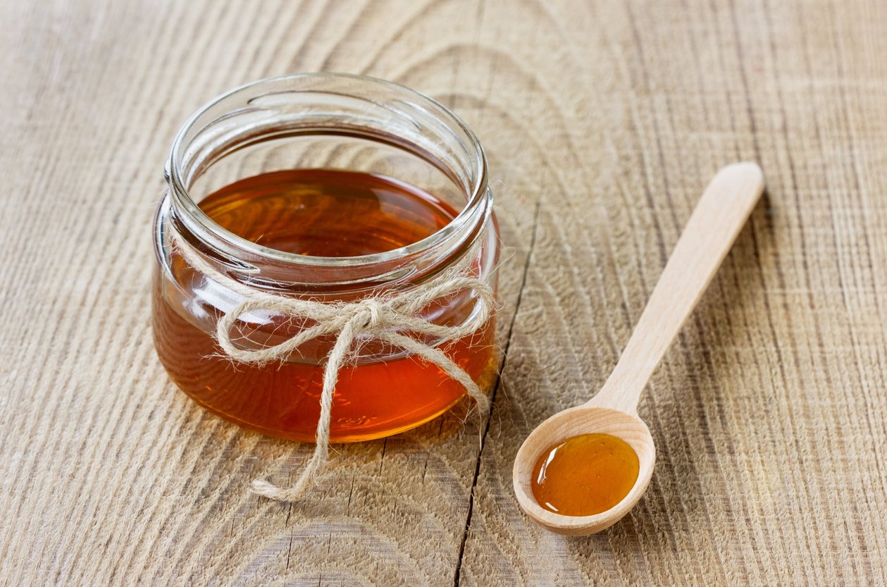 Honey in a spoon and jar on a rustic background